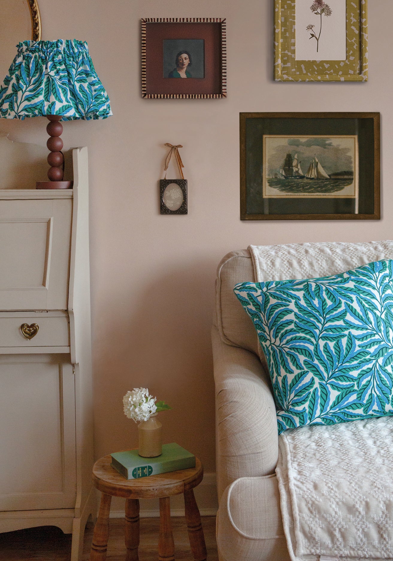 Living room with a beige sofa, green and white lampshade, and framed pictures on the wall.