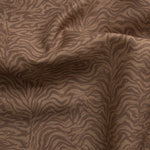 Detail of gently draped printed fabric with watercolor swirling stripe pattern in tonal warm terracotta brown.