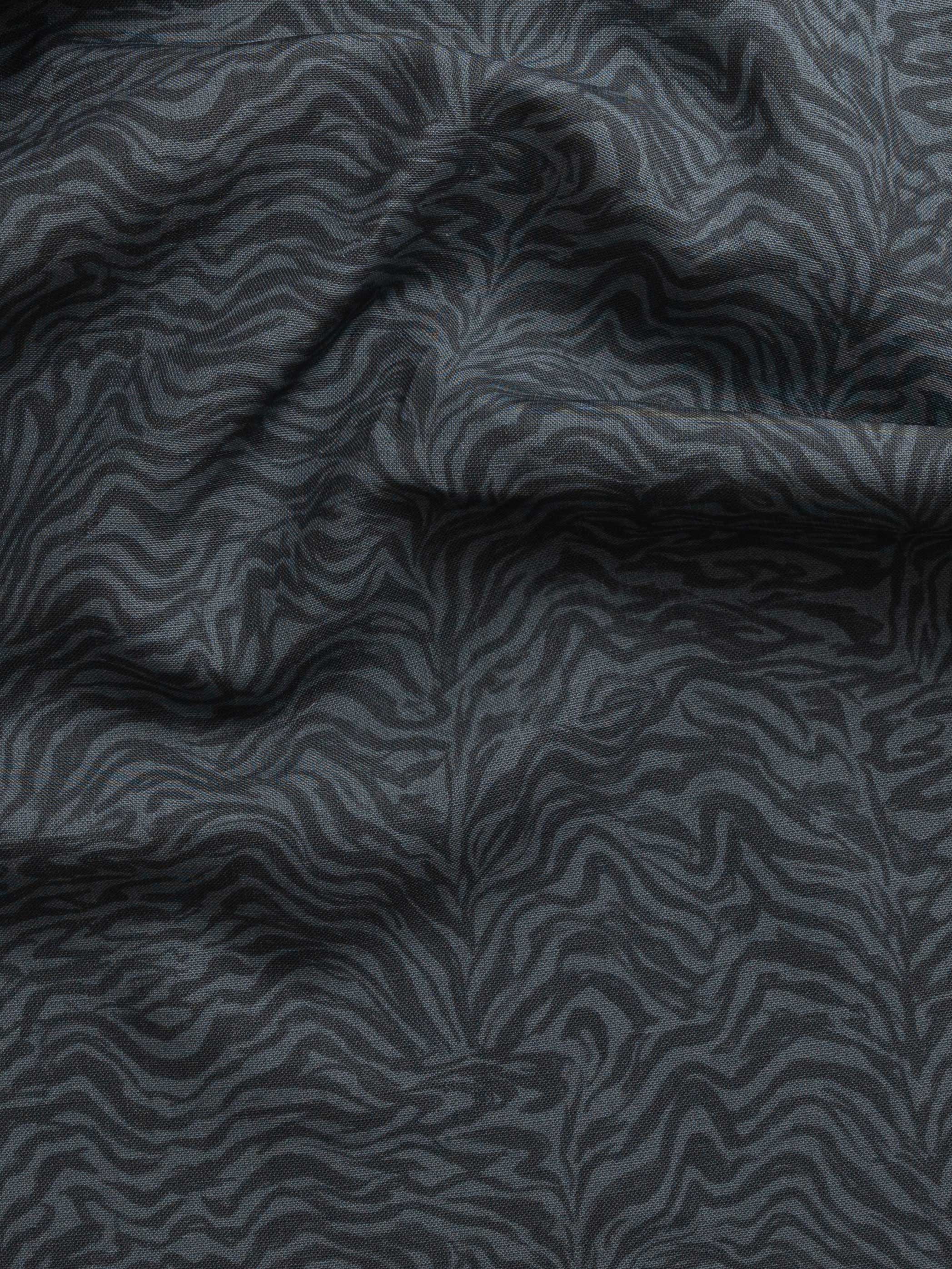 Detail of gently draped printed fabric with watercolor swirling stripe pattern in tonal navy blue.