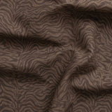 Detail of gently draped printed fabric with watercolor swirling stripe pattern in tonal warm brown.
