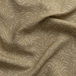 Detail of gently draped printed fabric with watercolor swirling stripe pattern in tonal muted ochre.