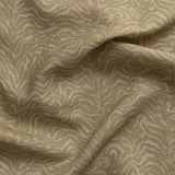 Detail of gently draped printed fabric with watercolor swirling stripe pattern in tonal muted ochre.