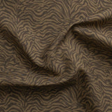 Detail of gently draped printed fabric with watercolor swirling stripe pattern in tonal brown.