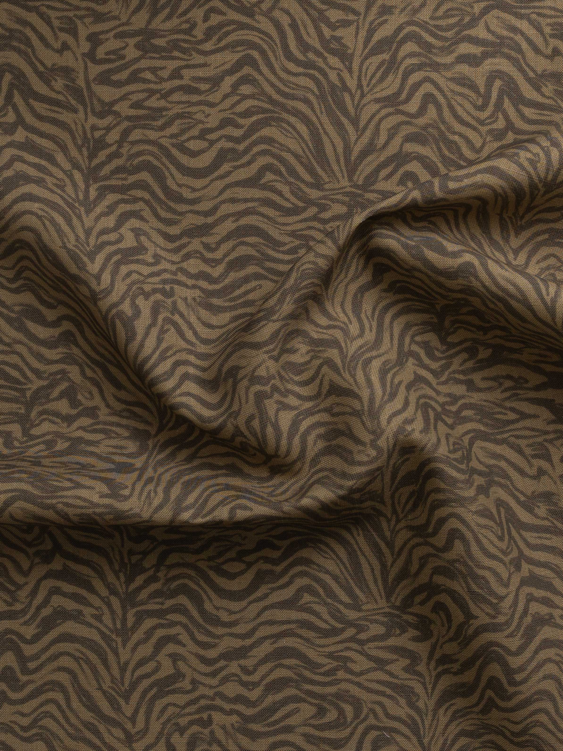 Detail of gently draped printed fabric with watercolor swirling stripe pattern in tonal brown.