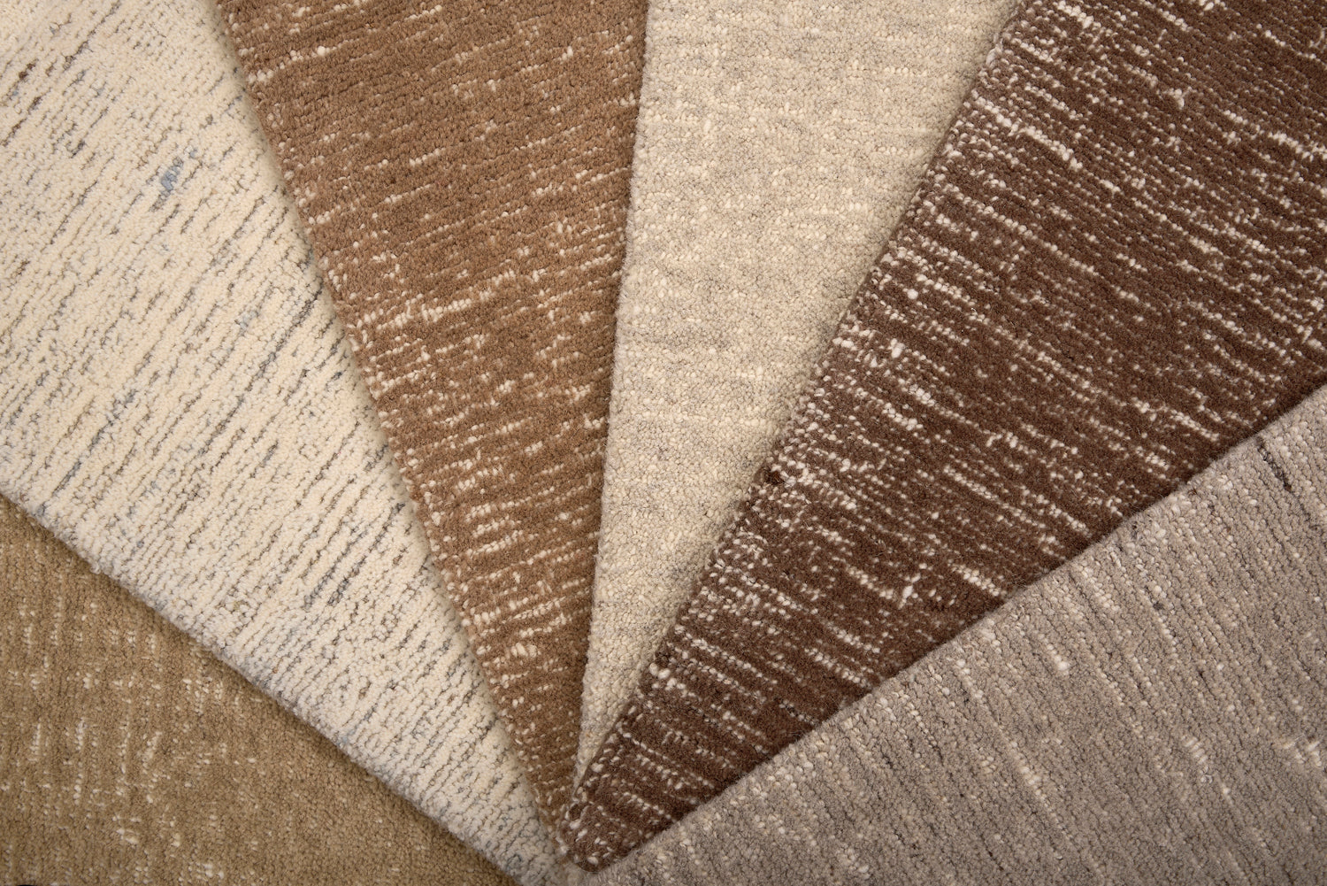 Array of textured carpet samples in neutral colors. 