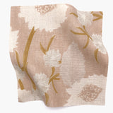 Square fabric swatch in a playful floral print in shades of pink, white and tan on a light pink field.