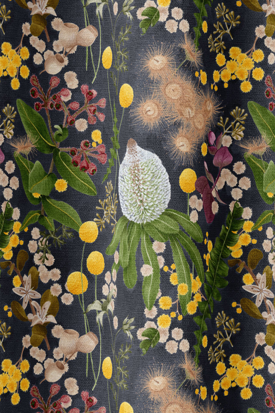 Draped fabric in a large-scale botanical print in shades of pink, yellow and green on a navy field.