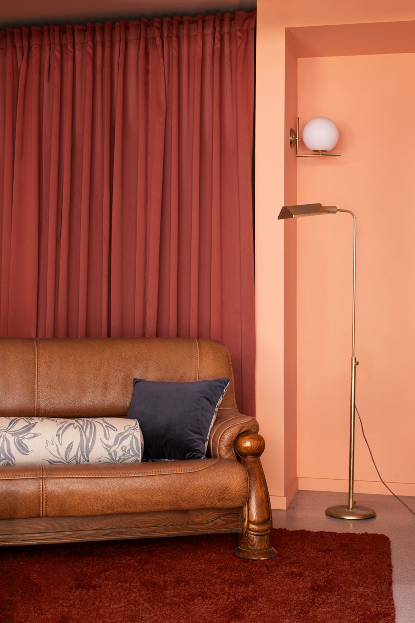 Modernist living room in orange and red tones with a leather couch and gray and cream throw pillows.