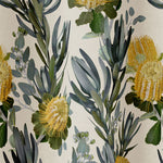 Draped fabric in a photorealistic floral print in shades of yellow, white and green on a cream field.