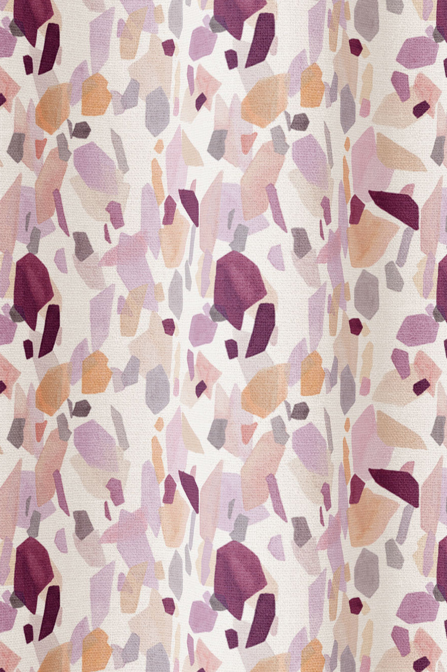 Draped fabric in an abstract shape print in shades of purple, maroon and orange on a cream field.