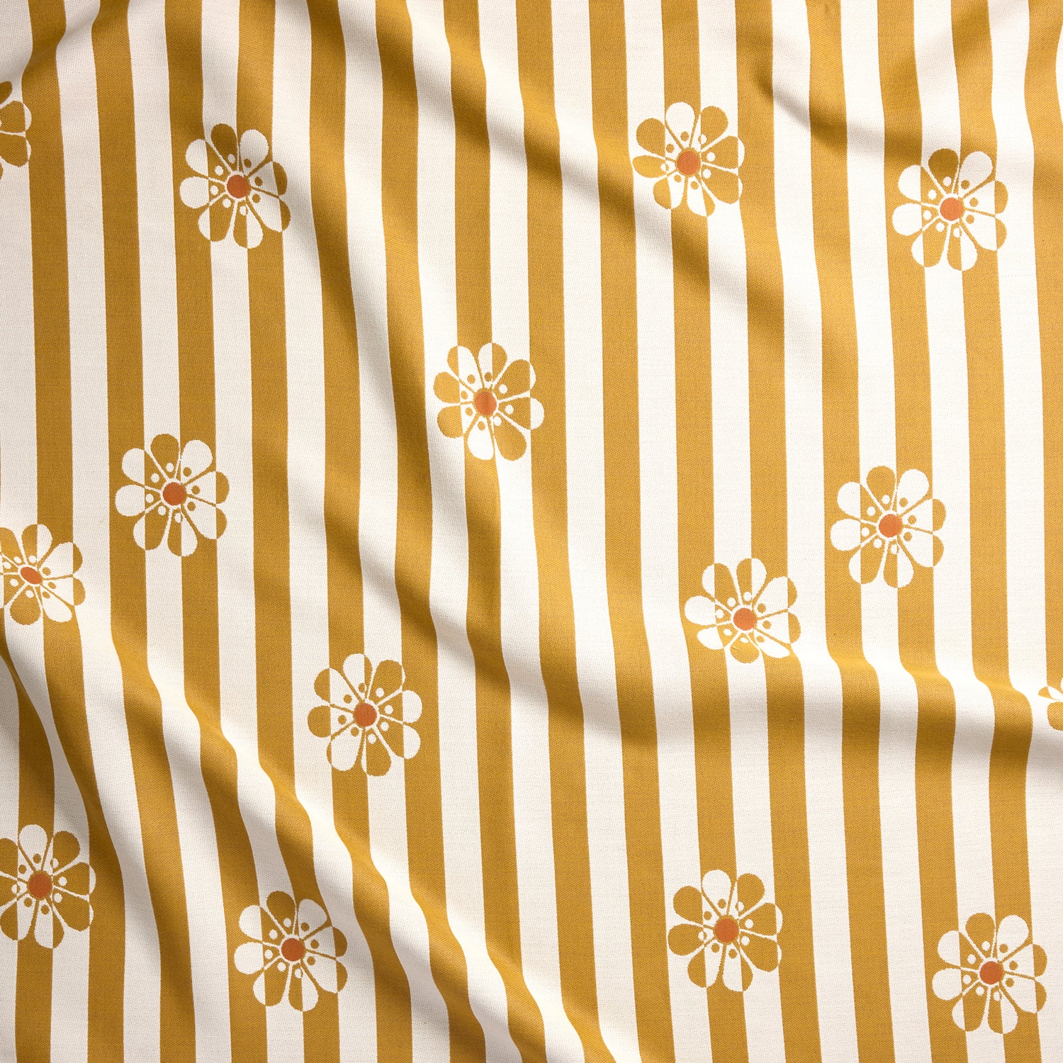 A close-up of a fabric surface with vertical mustard yellow and off-white stripes and repeated small daisy floral motifs.