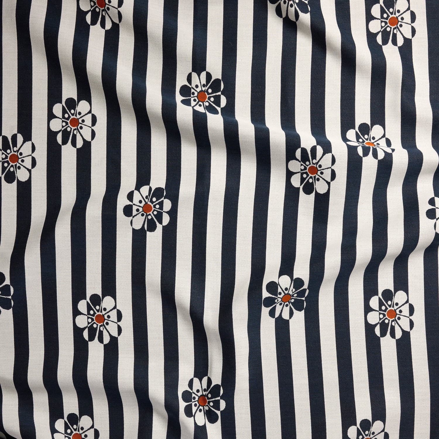 A close-up of a fabric pattern featuring vertical navy blue and off-white stripes with small daisy-like flowers in navy, white, and orange.