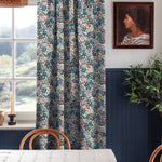 A cozy dining room tableau with a large window and curtains in a small-scale floral print.