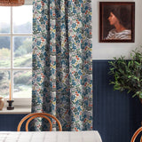 A cozy dining room tableau with a large window and curtains in a small-scale floral print.