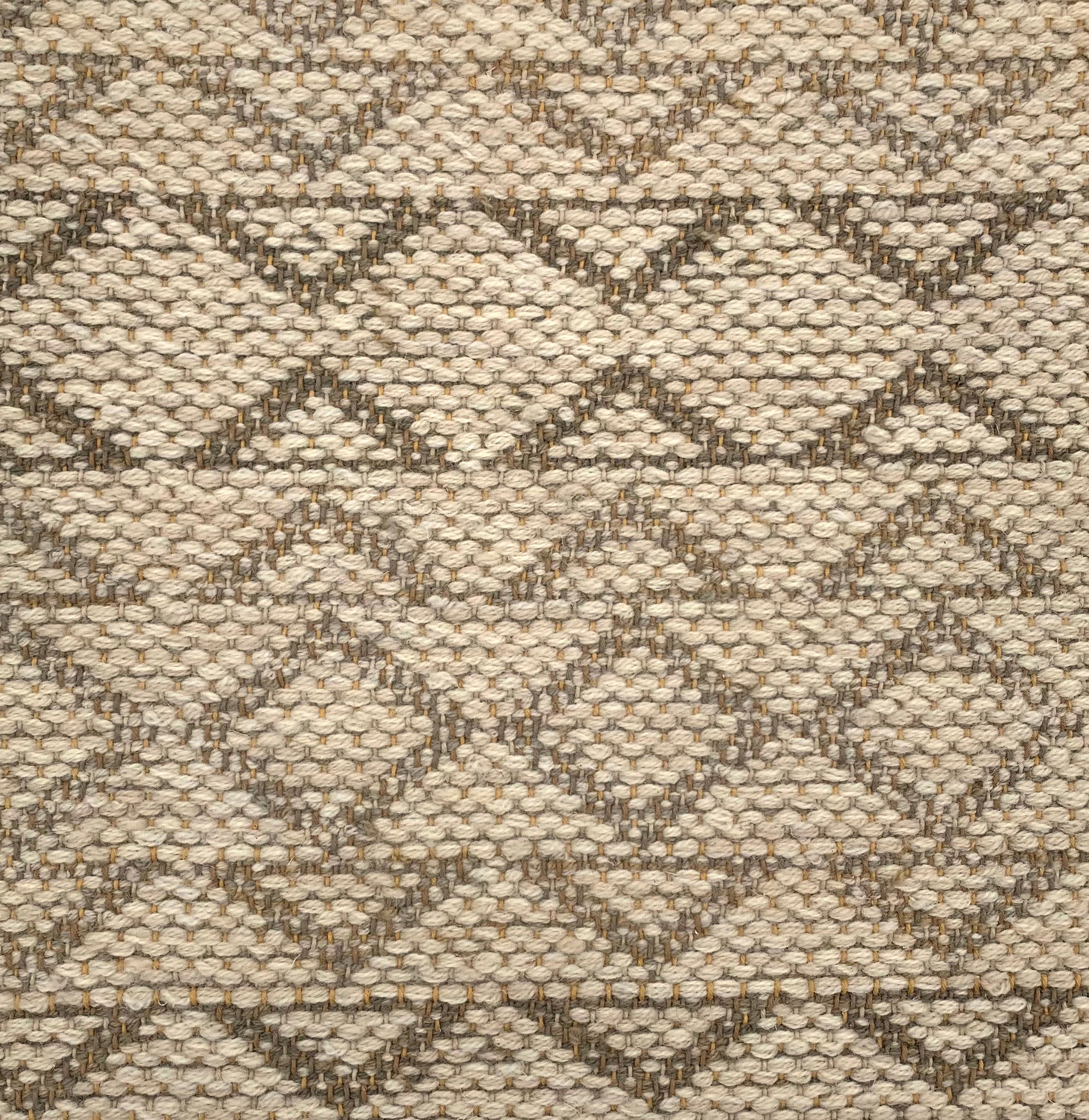 Handwoven rug detail in a geometric design in tan and brown