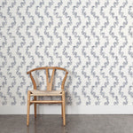 Wooden chair against a blue leaf stripe wallpapered wall