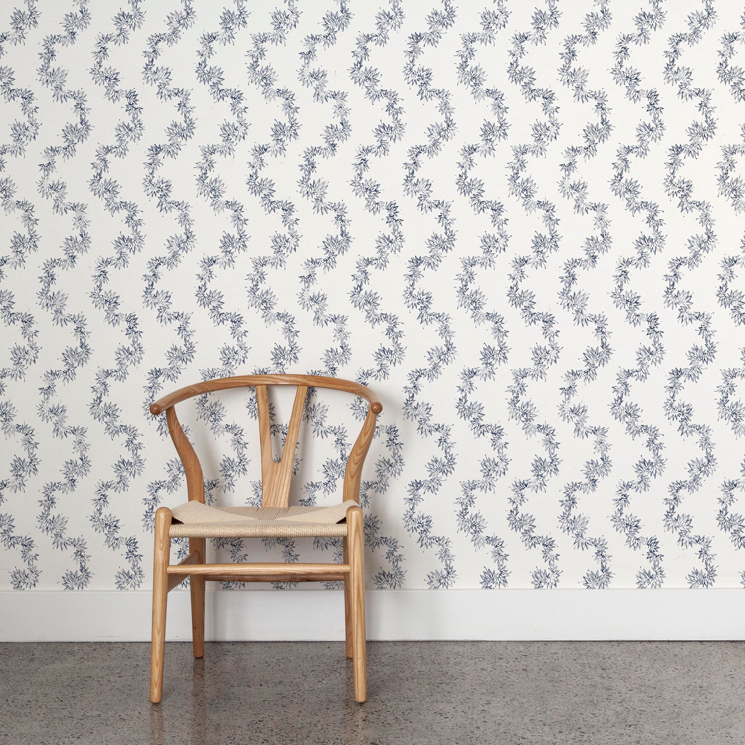 Wooden chair against a blue leaf stripe wallpapered wall