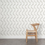Wooden chair against a wall with stylized leaf stripe wallpaper