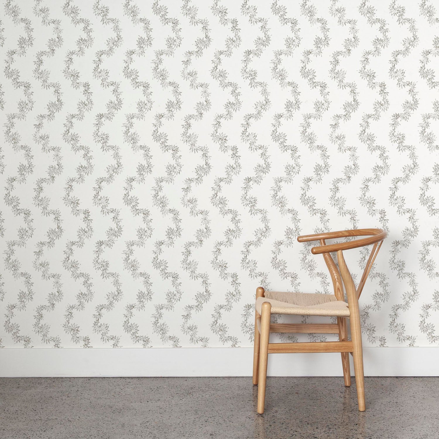 Wooden chair against a wall with stylized leaf stripe wallpaper
