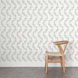 Wooden chair against a wall with stylized leaf stripe wallpaper