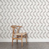 Wooden chair against wallpaper with stripe pattern of stylized ink black leaves on a cream background