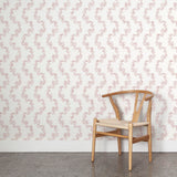 Wooden chair against wallpaper with stripe pattern of stylized pink leaves on a cream background
