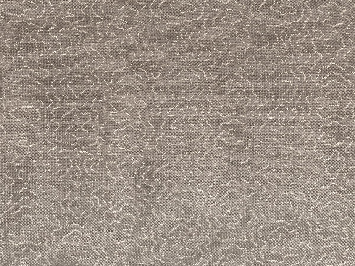 Detail of fabric in a minimalist wood grain print in cream on a gray field.