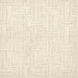 A close-up of a handwoven carpet with a repeating geometric maze in cream