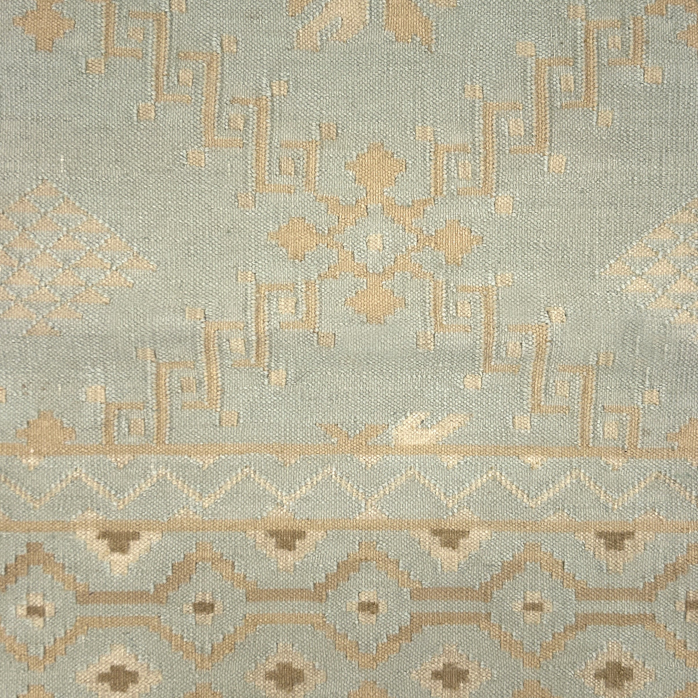 Handmade rug with geometric design on a light blue background