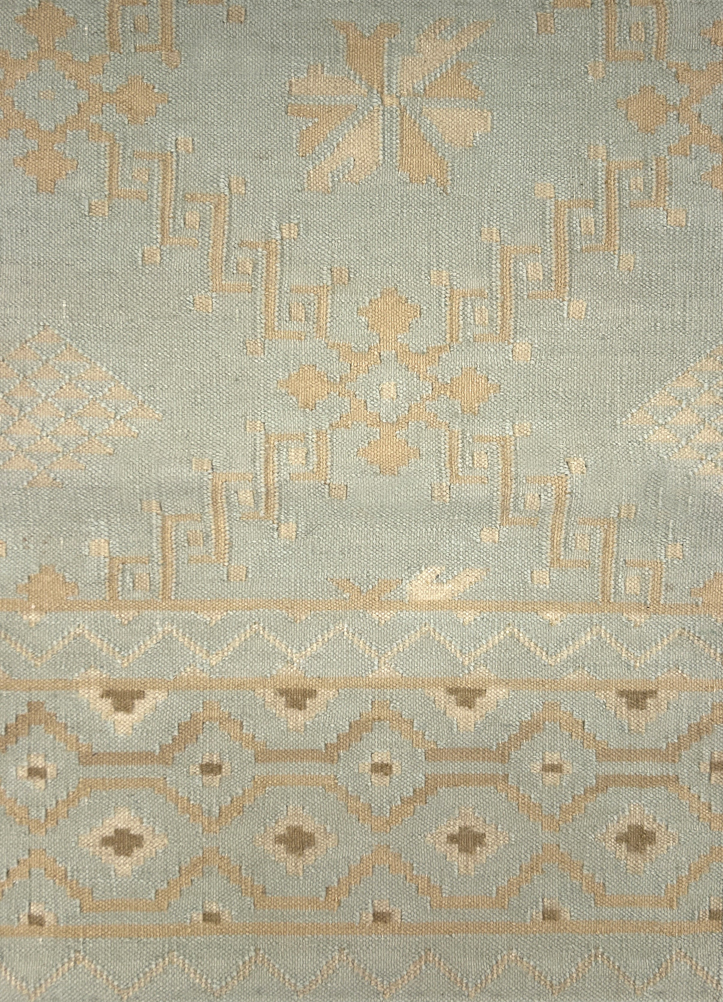Handmade rug with geometric design on a light blue background