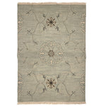 Handwoven rug sample with fringe in a floral filigree pattern in grey, brown and cream on a grey-blue field.