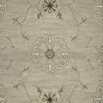 Close up of hand woven rug in a floral filigree pattern in grey, brown and cream on a grey-blue field.