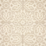 Close up of a handwoven rug in an ornate damask medallion design in cream on a beige field. 
