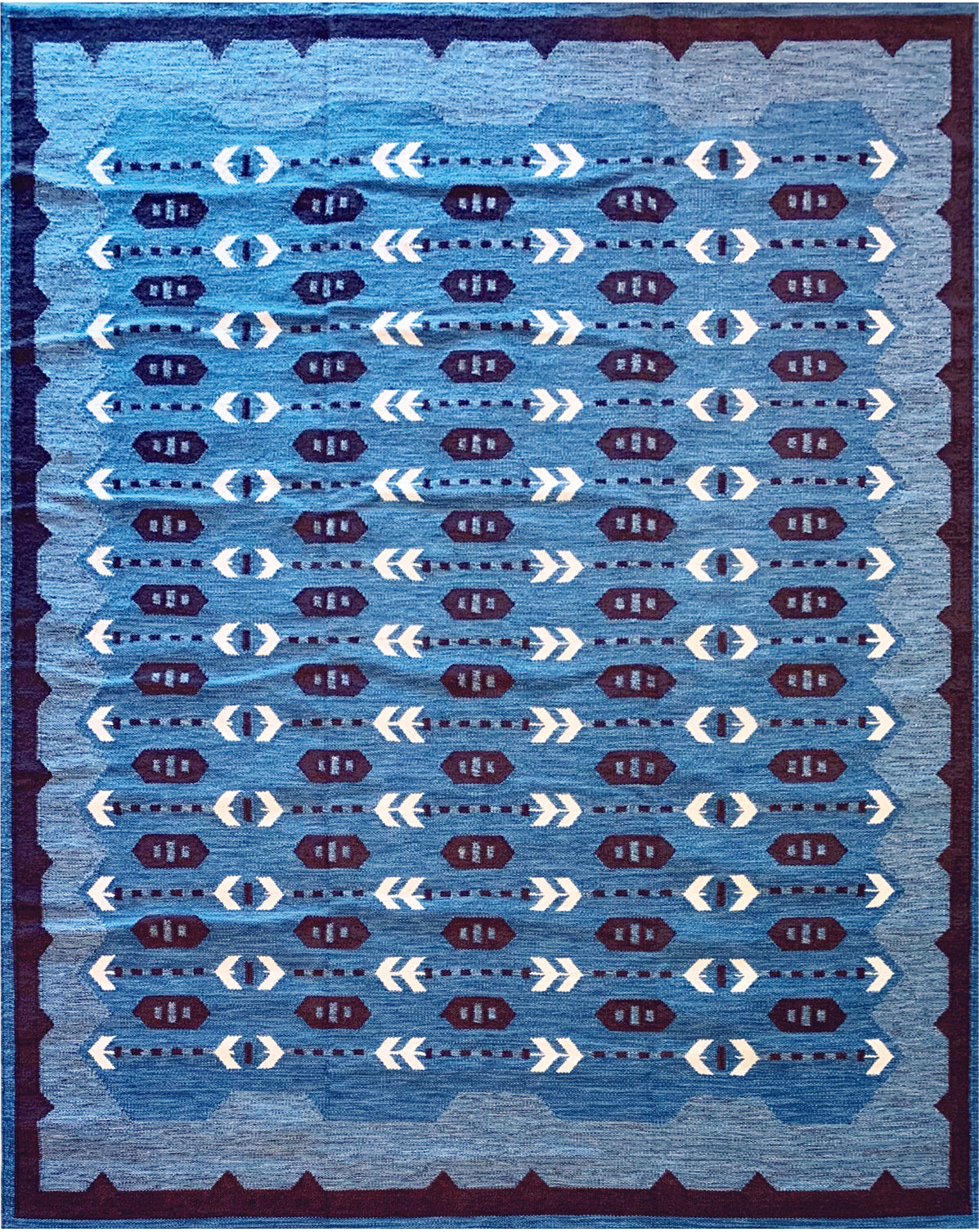 Handwoven rug in a Swedish arrow design in brown and white on a green field. 