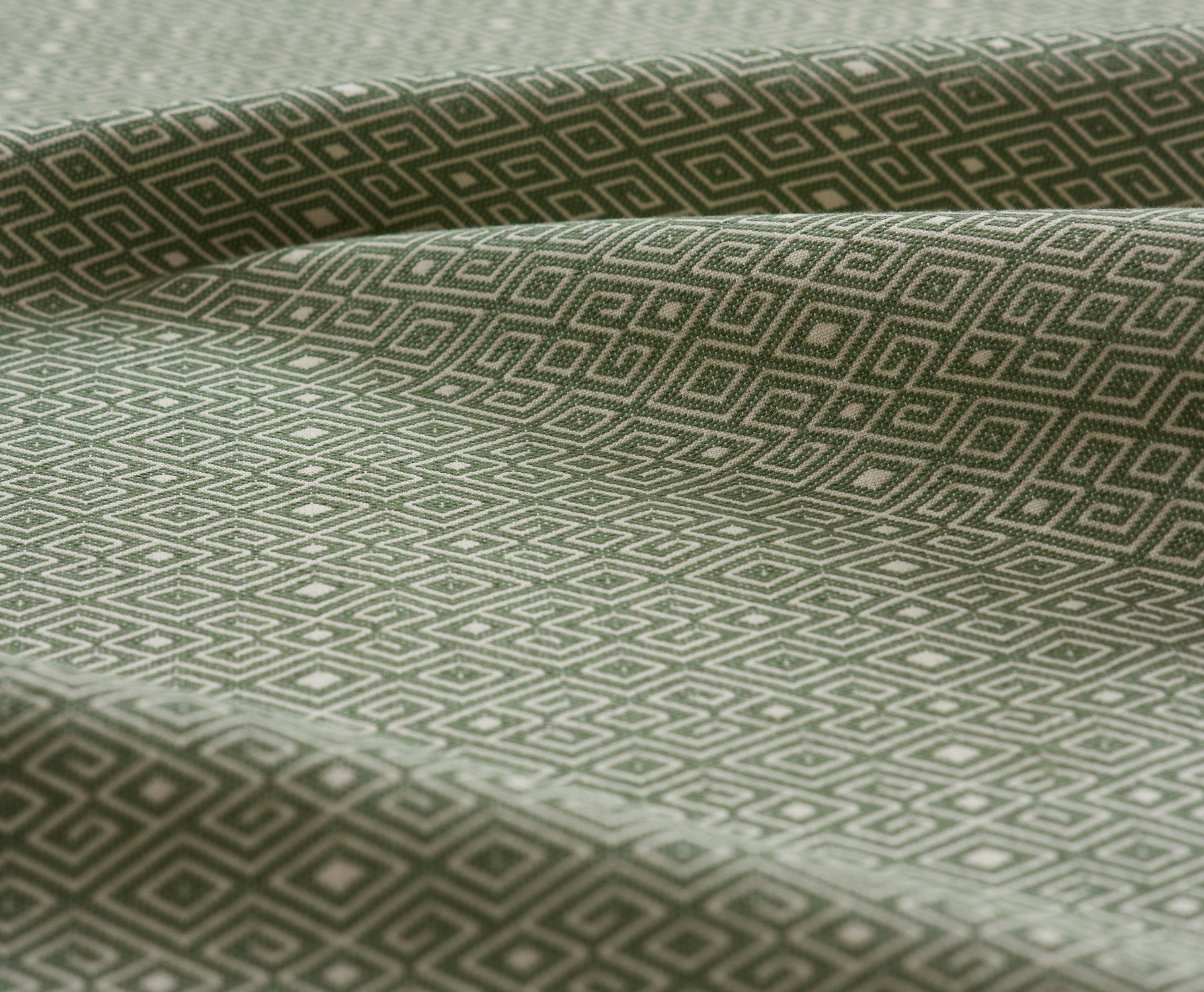 Lightly folded fabric swatch with a geometric diamond design in green.