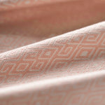 Close-up of light pink fabric with a subtle geometric pattern gently folded