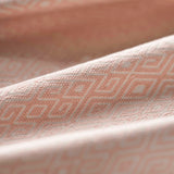 Close-up of light pink fabric with a subtle geometric pattern gently folded