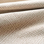 Close-up of textured beige fabric with geometric pattern lightly folded. 