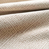 Close-up of textured beige fabric with geometric pattern lightly folded. 