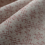 Close-up of fabric with a red geometric pattern on a beige background lightly folded