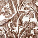 Close up of gently draped printed linen with bold high contrast tropical banana leaf pattern in dark brown on white. 