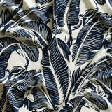 Close up of gently draped printed linen with bold high contrast tropical banana leaf pattern in navy blue on white. 