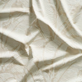 Close up of gently draped printed linen with bold high contrast tropical banana leaf pattern in white on tan.