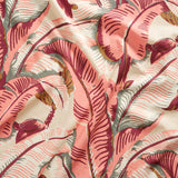 Close up of gently draped printed linen with bold banana leaf in shades of coral pink, magenta, grey and tan on cream,