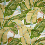 Close up of gently draped woven Indoor-Outdoor fabric with bold banana leaf in yellow, green, pink and orange on white.