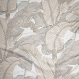 Close up of gently draped woven Indoor-Outdoor fabric with bold banana leaf in shades of beige on white.