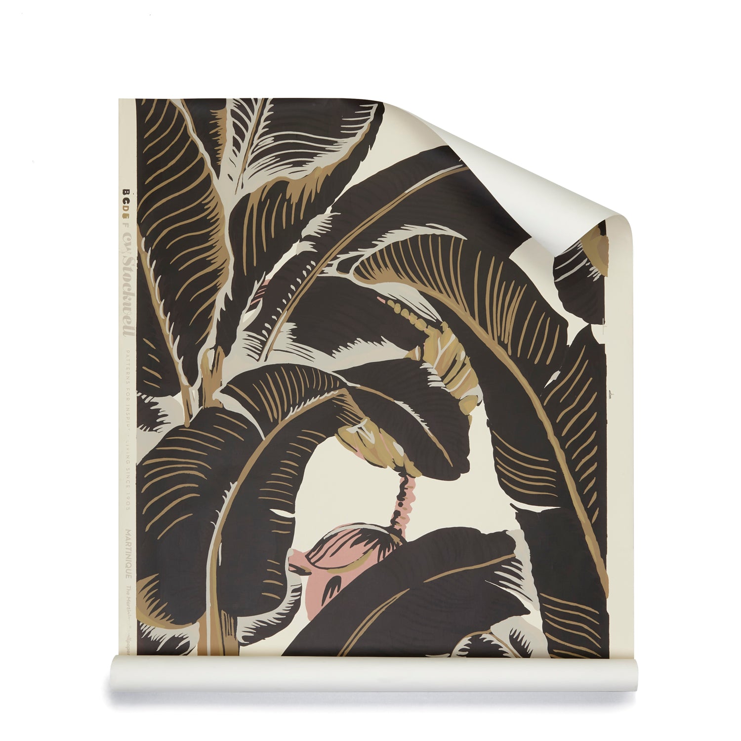 A roll of banana leaf pattern wallpaper in dark brown, beige, and cream with a soft pink floral  accent. 