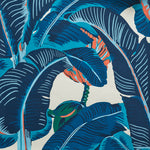 Close up of banana leaf pattern wallpaper featuring large tropical leaves in navy, teal and coral on an off-white background.