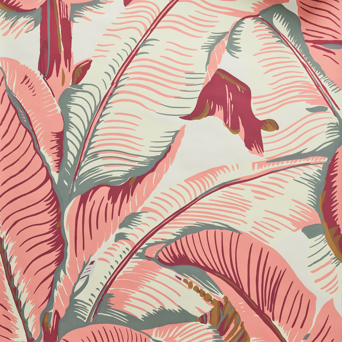 Close up of banana leaf pattern wallpaper featuring large tropical leaves in terracotta pink, cream, and muted gray-green tones on a light cream background.