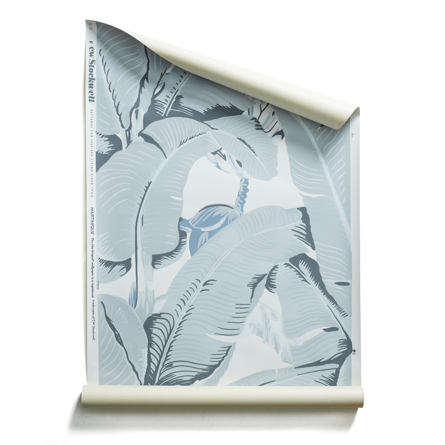 A roll of a tropical wallpaper pattern featuring large, stylized palm leaves in shades of slate blue-gray and off-white.
